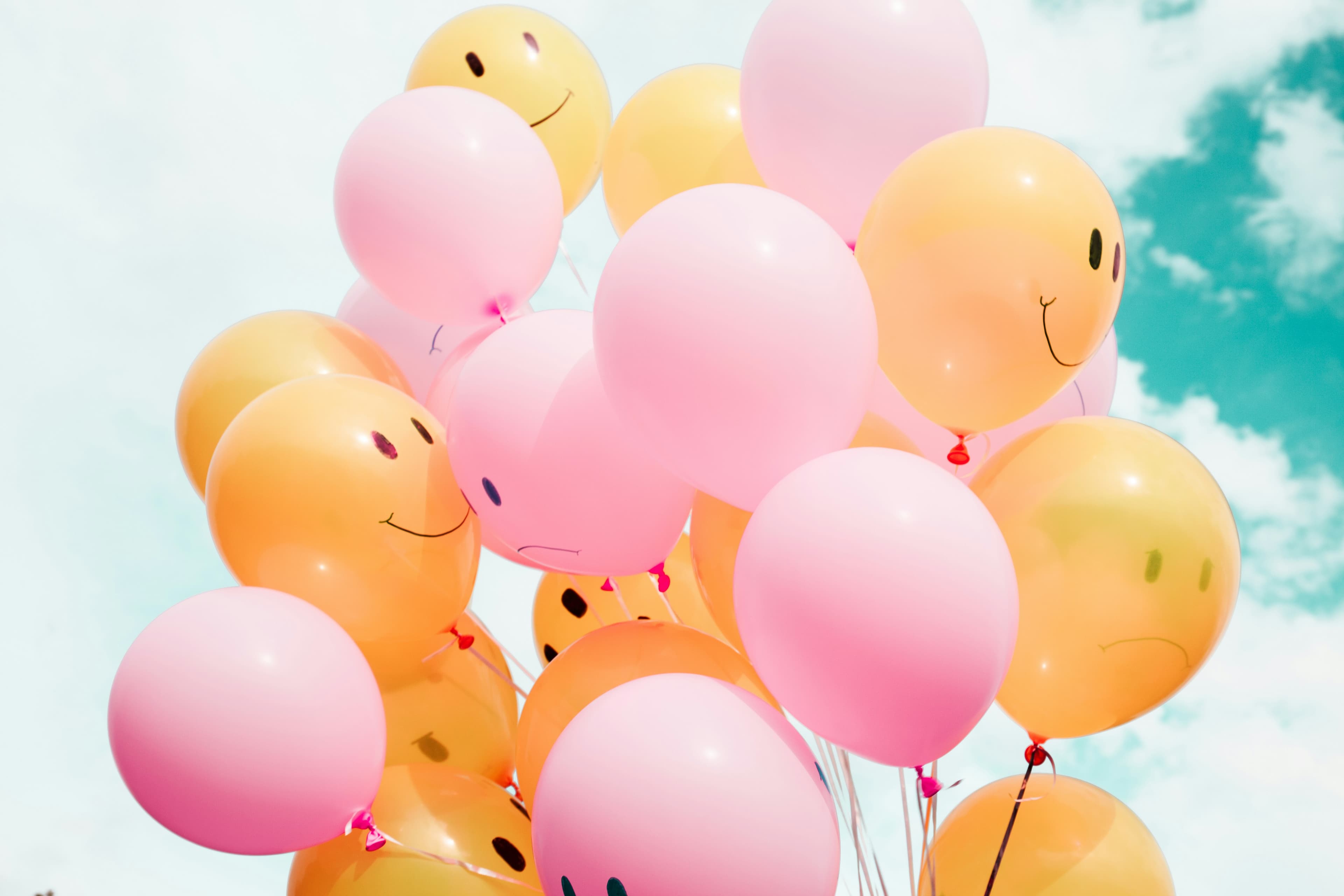 Globos rosados y naranjas con helio contra el cielo