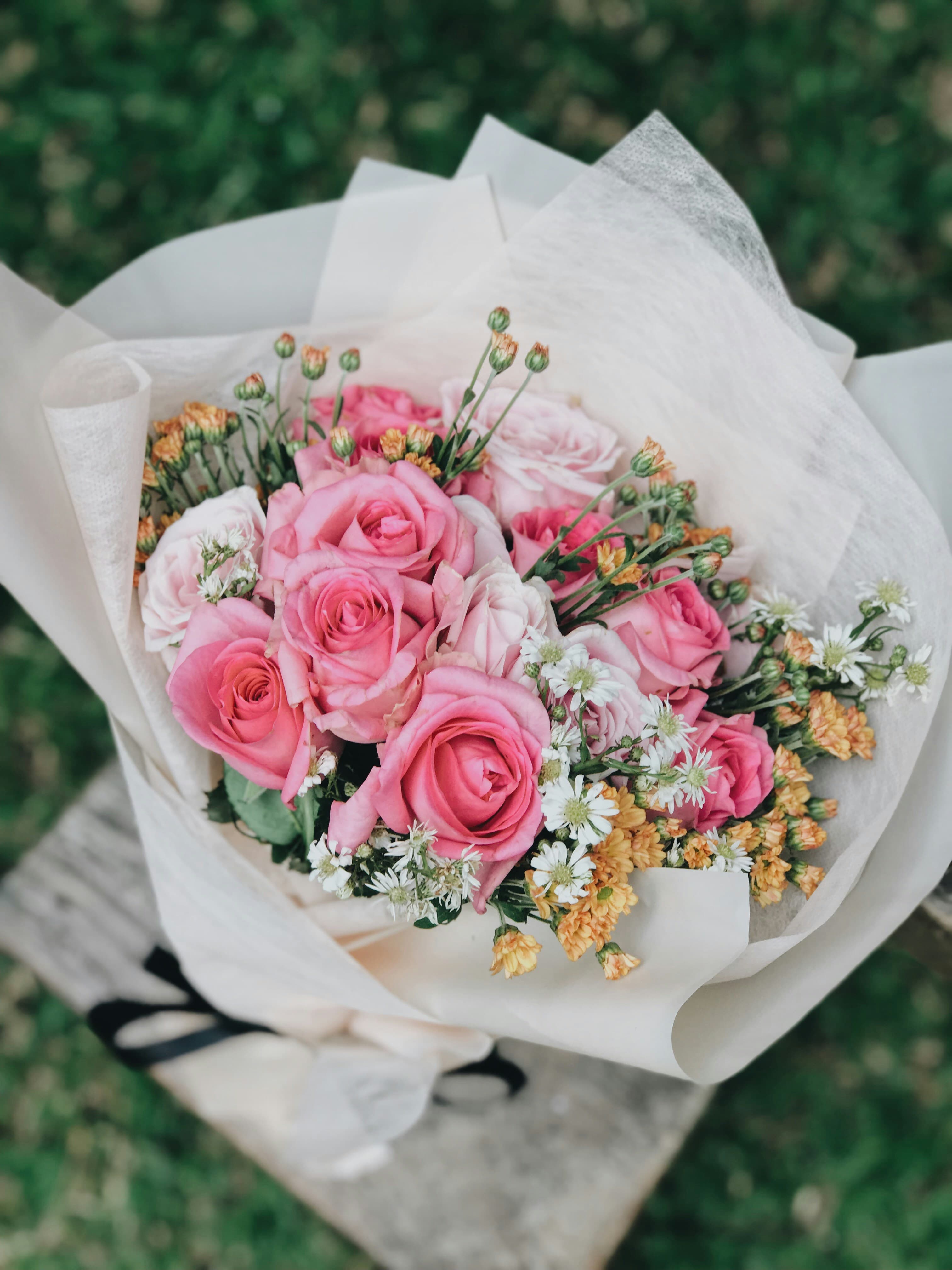 Ramo de rosas rosadas y blancas envuelto en papel