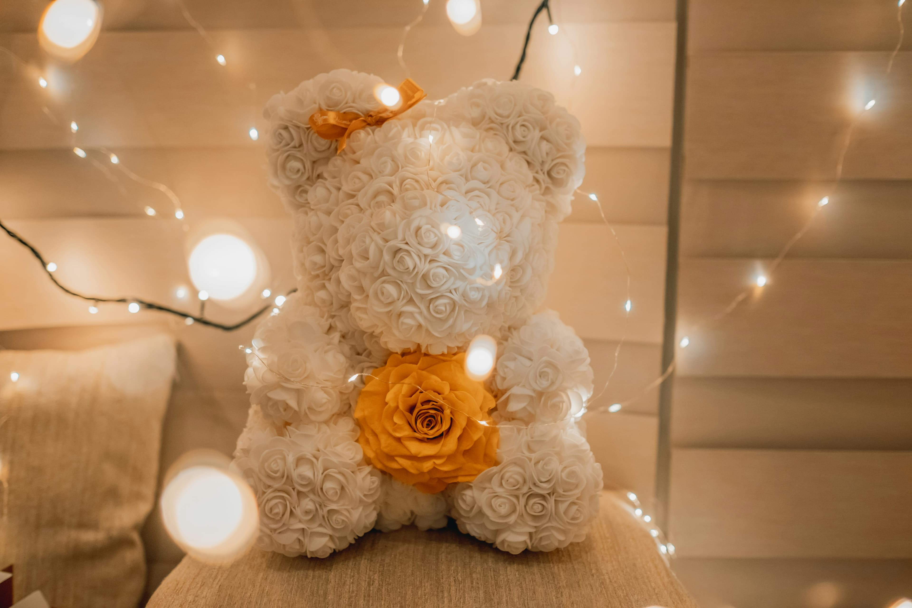 Oso de peluche blanco con una rosa dorada en el pecho