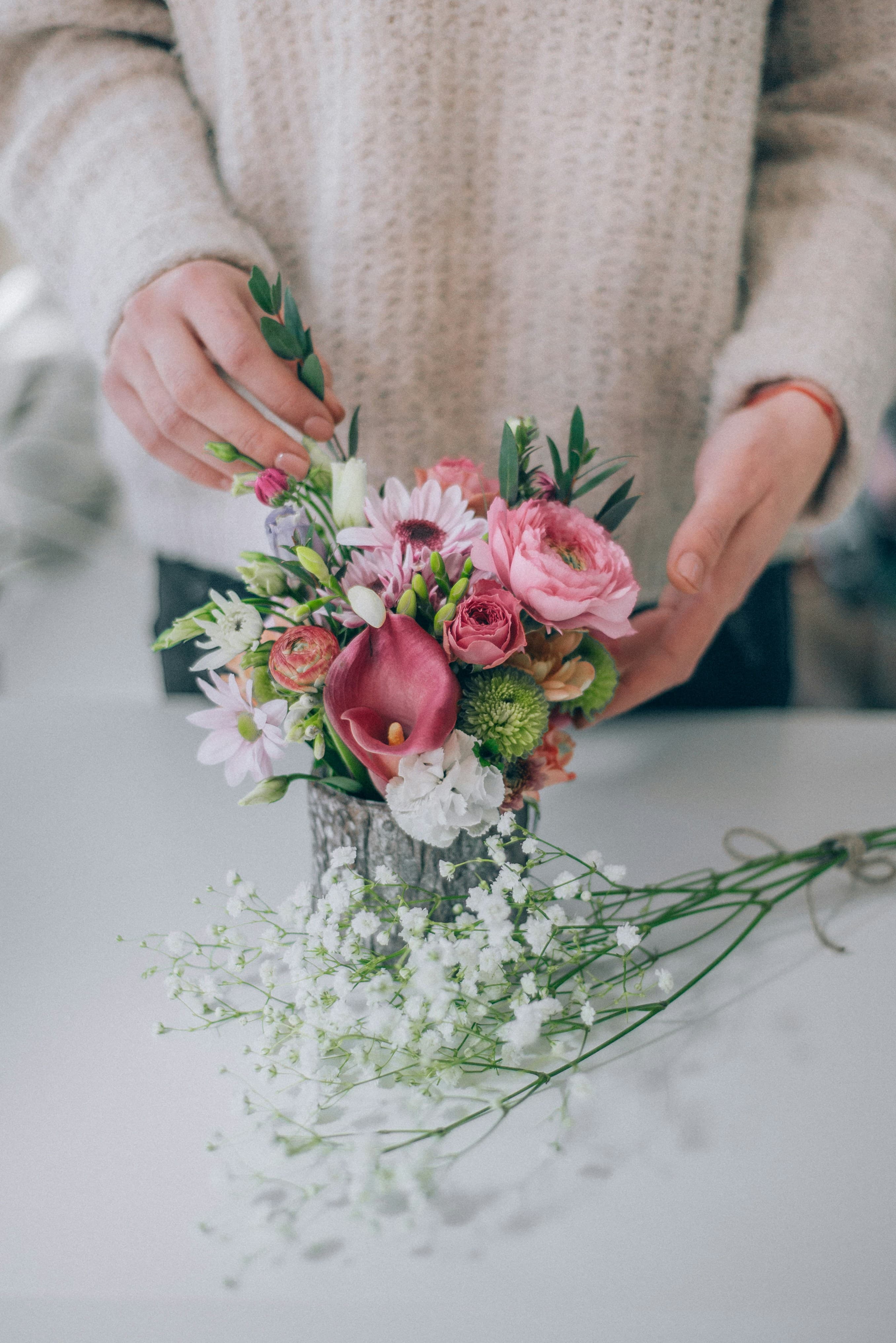 Manos de florista acomodando un arreglo de rosas rosadas