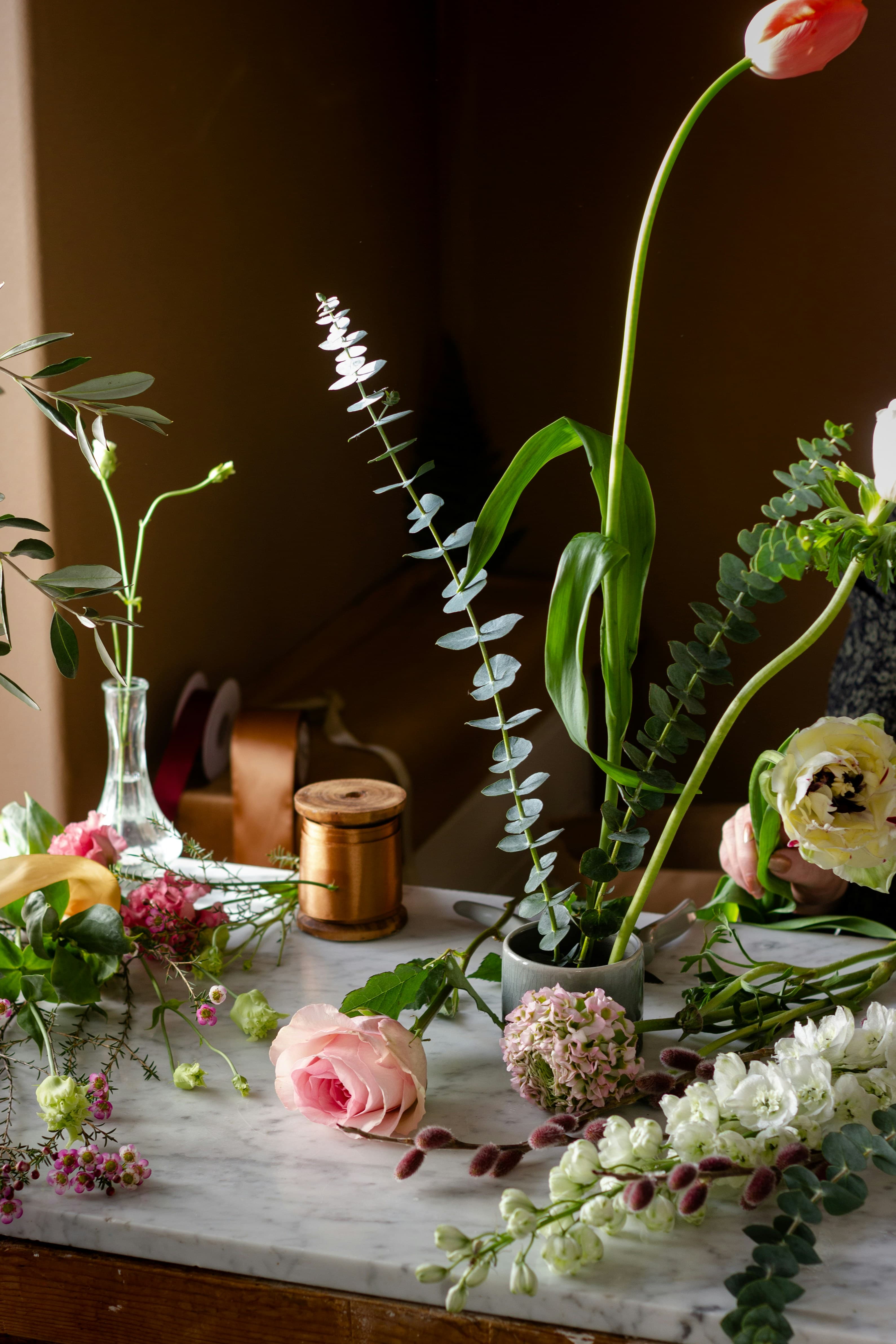 Mesa de floristería con carrete de cinta, flores y tijeras