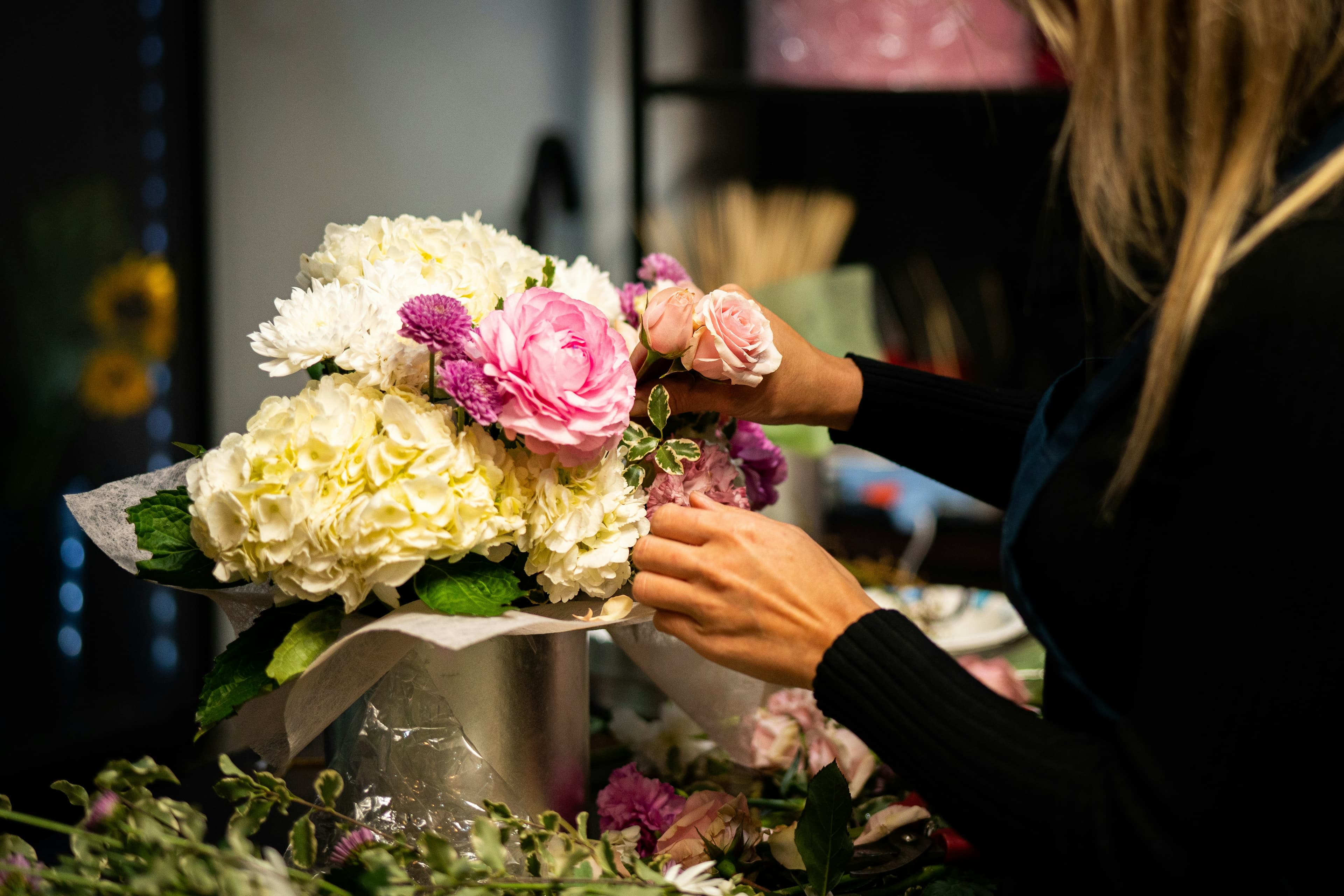 Florista armando un arreglo de hortensias y rosas